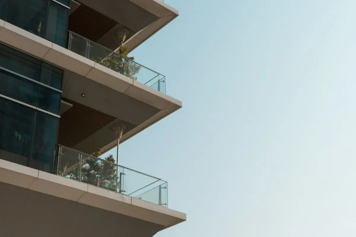 Concrete balconies with glass rails projecting into a clear sky
