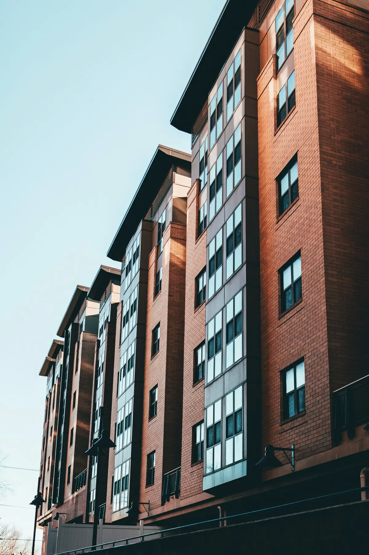 A tall brick apartment building with glass corner balconies