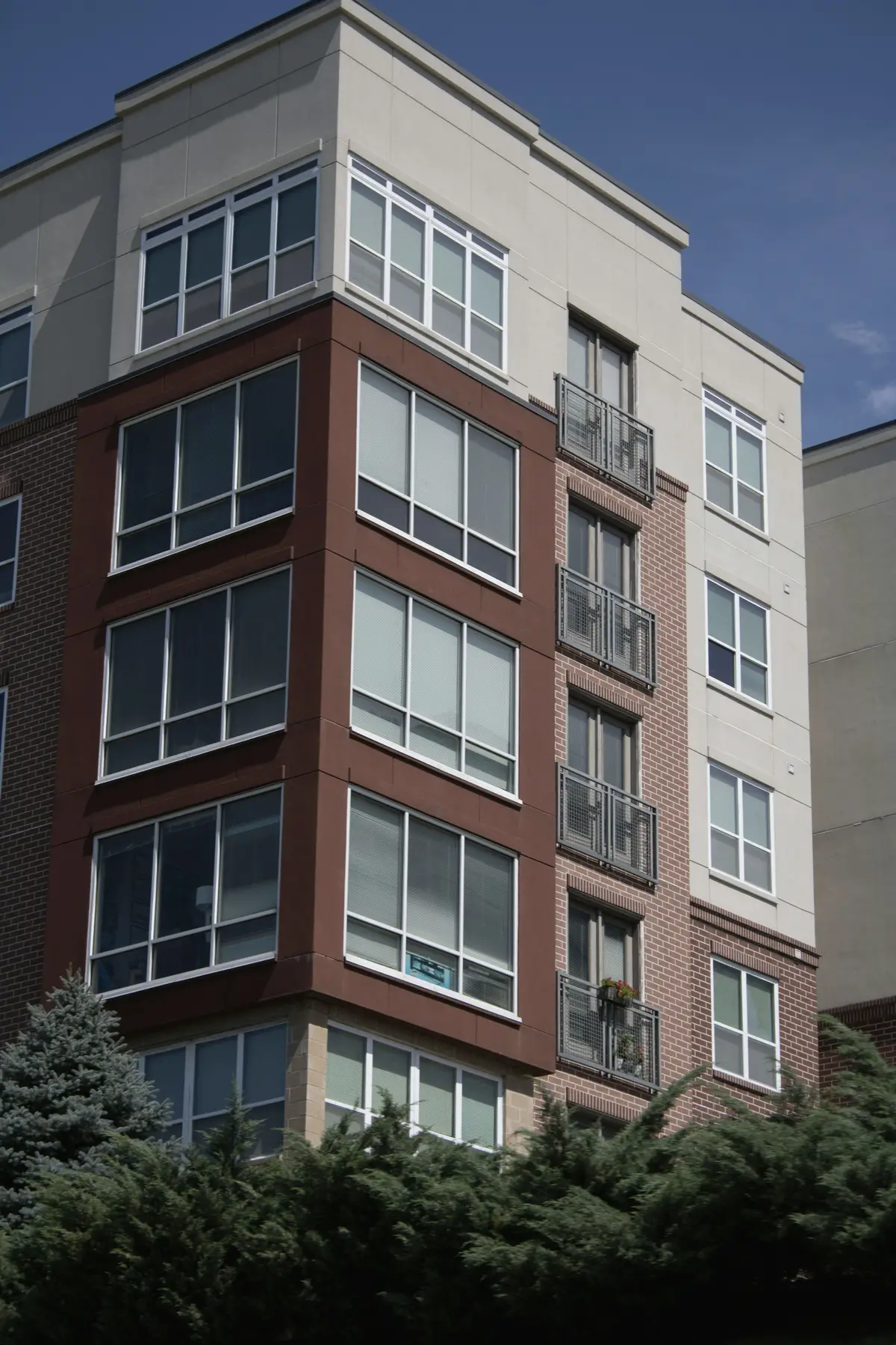 A brick and light-panel residential building with corner windows and balconies