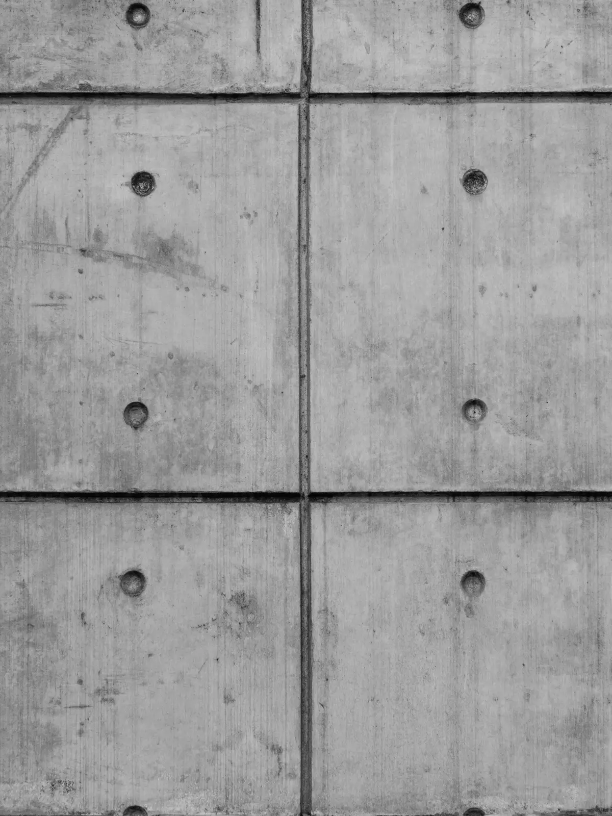 A concrete wall with a grid of form-tie holes