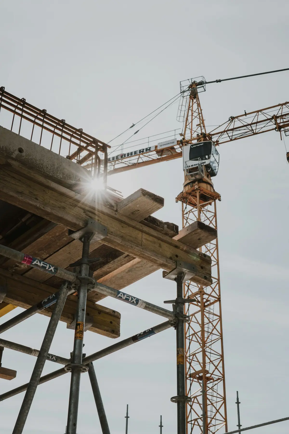 Timber formwork and a tower crane on a construction site against the sky