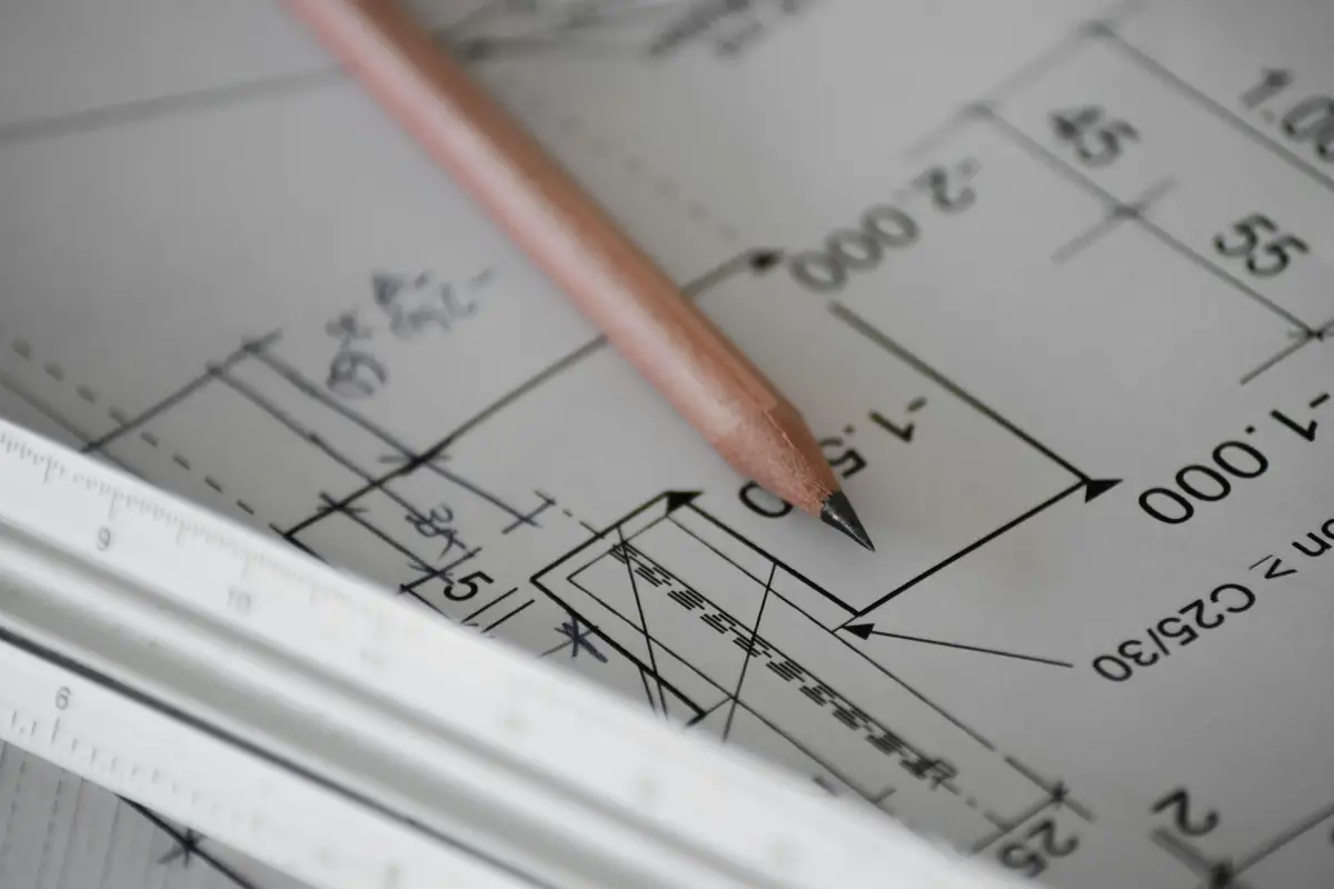 A pencil resting on a technical drawing with dimensions