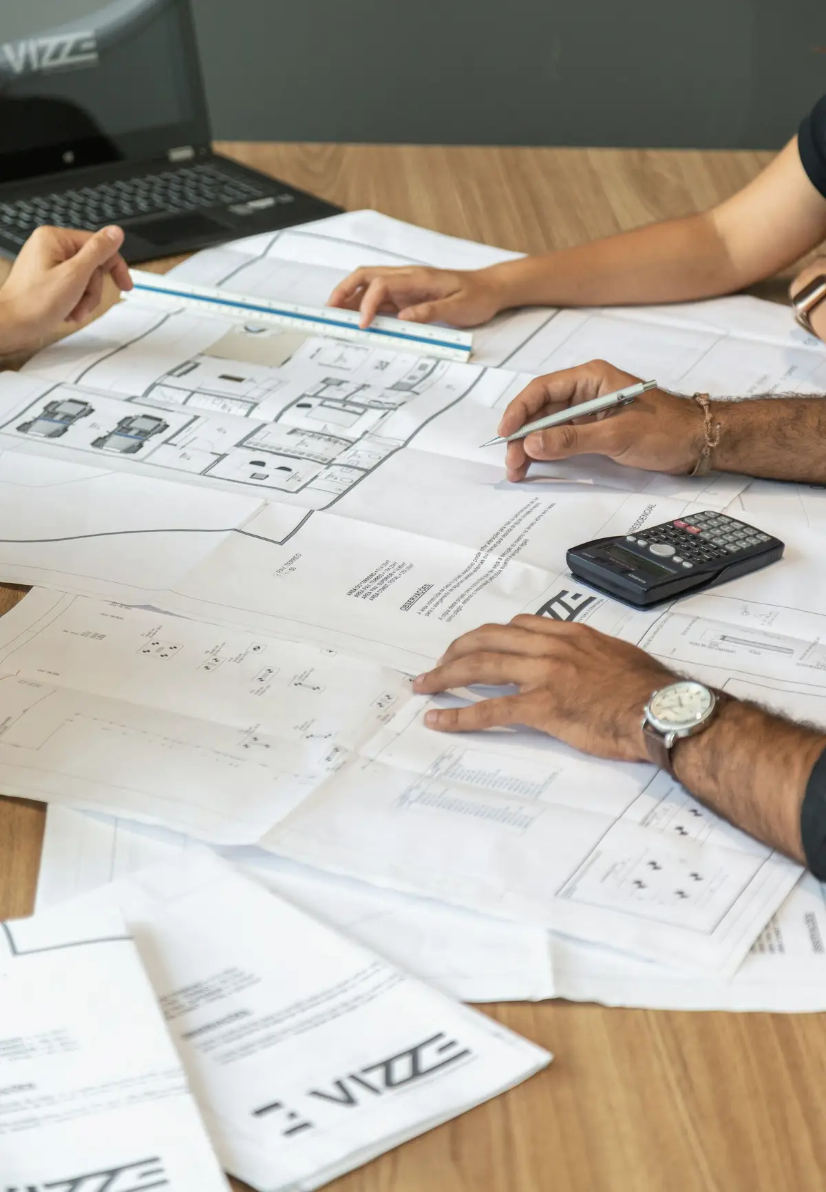Two people reviewing architectural drawings with a calculator