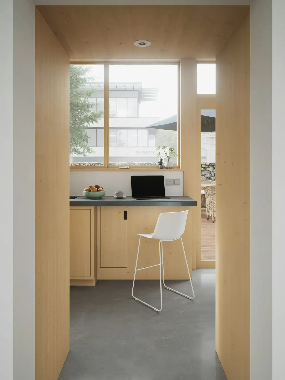 A plywood-lined work nook with a window and a white stool