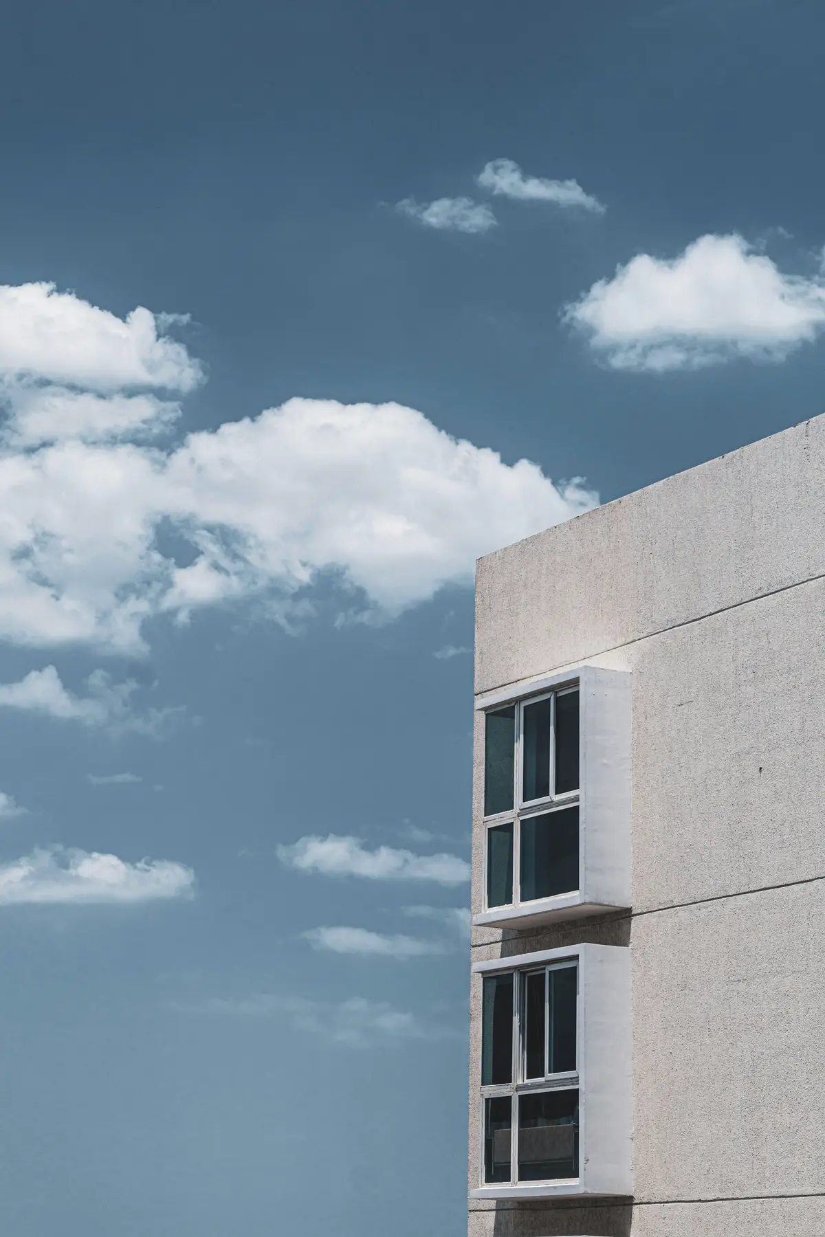 Pale stone building corner against a blue sky with clouds
