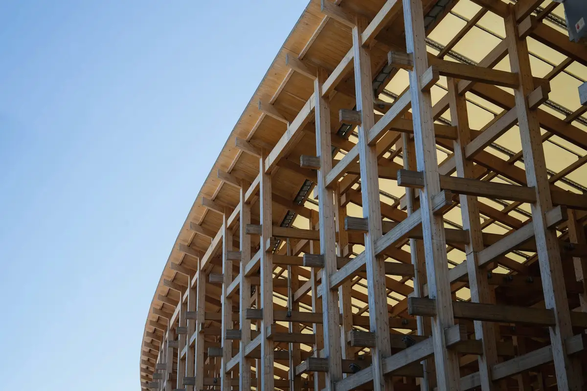 A curved timber lattice structure against a clear sky